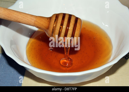 Honig wird mit einem speziellen Holzlöffel tropft. Stockfoto