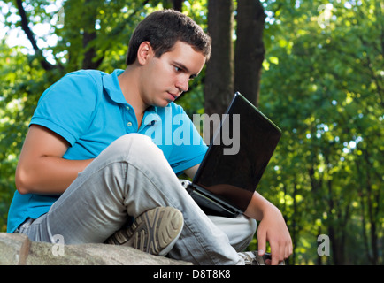 junger Mann mit Laptop im park Stockfoto