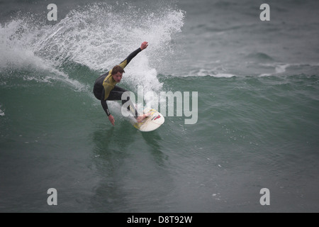 FISTRAL STRAND, NEWQUAY, CORNWALL. Ein Surfer, plantschen in einem Zug auf die Oberseite einer Welle. Stockfoto