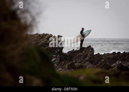 FISTRAL STRAND, NEWQUAY, CORNWALL. Ein Surfer am Ufer zu Fuß in Richtung Meer mit einem Surfbrett unter dem Arm. Stockfoto