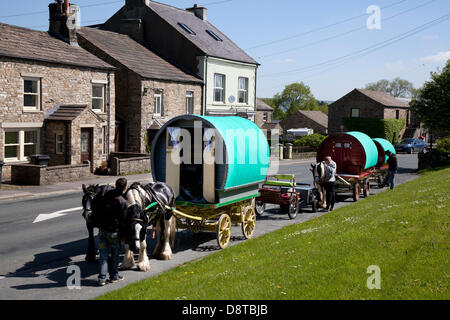 Karawanen für Reisende aus der Romantik; Zigeunerwagen mit Yardos- oder Bow Top-Wagen vor Ort in Bainbridge auf dem Weg zur Appleby Horse Fair in Cumbria. Die Messe ist ein jährliches Treffen von Zigeunern und Reisenden, das in der ersten Juniwoche stattfindet und seit der Regierungszeit von James II. Stattfindet, der 1685 eine königliche Charta für eine Pferdemesse in der Nähe des Flusses Eden erteilte. Stockfoto