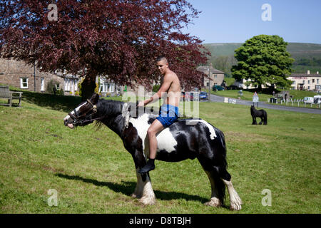 Zigeunerreisende in Bainbridge, Richmondshire, North Yorkshire, Großbritannien. Juni 2013. Brad Hill, 17 auf einem Cob-Pferd auf dem Dorfgrün reiten ein Mitglied der Wandergemeinde auf dem Weg zur Appleby Horse Fair in Cumbria. Die Messe ist ein jährliches Treffen von Zigeunern und Reisenden, das in der ersten Juniwoche stattfindet und seit der Regierungszeit von James II. Stattfindet, der 1685 eine königliche Charta für eine Pferdemesse in der Nähe des Flusses Eden erteilte. Stockfoto