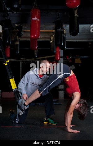 Persönliche Trainer Rhys John, mit Reihe von Körper Gewicht Übungen in einem Fitnessstudio trainieren. Stockfoto