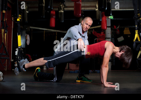 Persönliche Trainer Rhys John, mit Reihe von Körper Gewicht Übungen in einem Fitnessstudio trainieren. Stockfoto