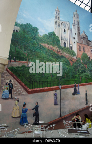 Paar sitzt unter einem Café Wandbild zeigt den Hauptplatz und die Kathedrale in Merida, Yucatan, Mexiko Stockfoto
