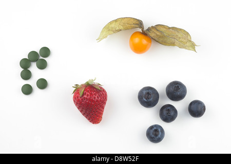 Frische goldene Beeren, Erdbeeren, Heidelbeeren und Chlorella-Tabletten auf weißem Hintergrund Stockfoto