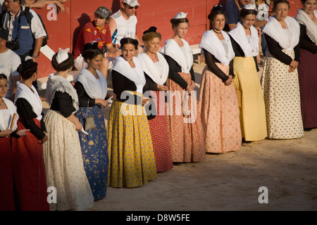 Eine Reihe von Frauen in der Arena stehen gekleidet in Arlésienne Kostüm vor einem Stierkampf, Arles, Frankreich Stockfoto