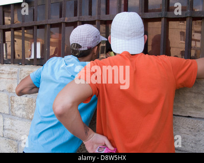 Zwei junge Männer Rückansicht tragen Baseball-Kappen und T-shirts an einem Kiosk am Arena, Arles, Frankreich Stockfoto