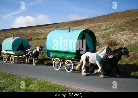 Wohnwagen für Reisende aus der Romandie; Vintage Gypsy Wagon Vardo, mit Bow-Top-Stoff bedeckter Wohnwagen; Lieferwagen und Wohnwagen; Mitglieder der Reisesgemeinschaft auf dem Weg zur Appleby Horse Fair in Cumbria. Die Messe ist ein jährliches Treffen von Zigeunern und Reisenden, das in der ersten Juniwoche stattfindet und seit der Regierungszeit von James II. Stattfindet, der 1685 eine königliche Charta für eine Pferdemesse in der Nähe des Flusses Eden erteilte. Stockfoto