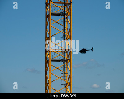 Baukran und ein Hubschrauber mit einem blauen Himmel Stockfoto