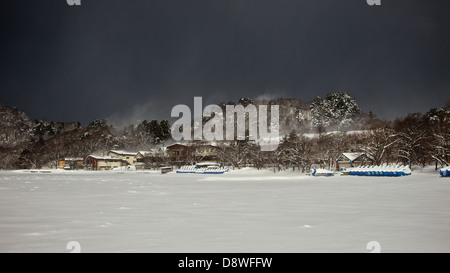 Dunkel bewölkter Himmel umhüllt einen gefrorenen See Towada - alle Bootfahren Aktivitäten kommen zum Stillstand im Winter Stockfoto