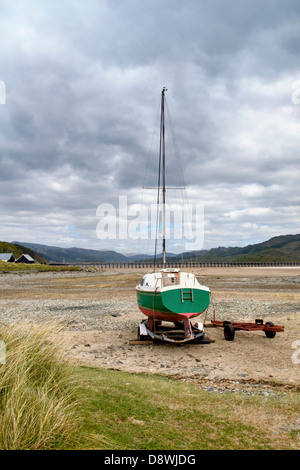 Fairboune Strand an der Küste von Barmouth Bay, Gwynedd, Wales, UK mit kleinen Boot und Barmouth Mautbrücke in der Ferne Stockfoto