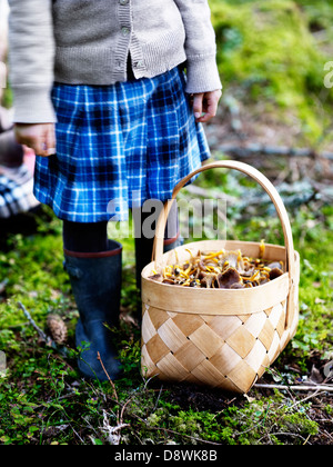 Mädchen mit Korb voller Pilze stehen im Wald Stockfoto