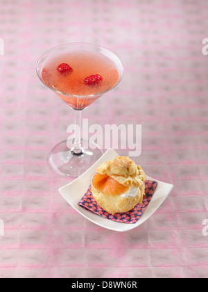 Champagner-Himbeer cocktail, Choux Brötchen garniert mit Frischkäse und Räucherlachs Stockfoto