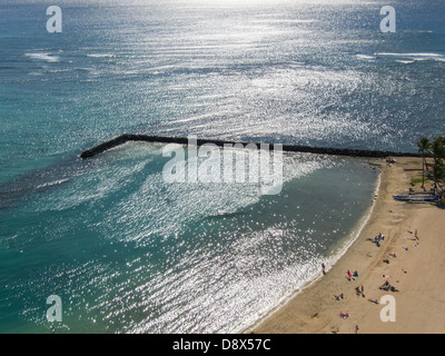 Steg am Strand von Waikiki mit Sonnenlicht funkelt im Wasser gespiegelt Stockfoto