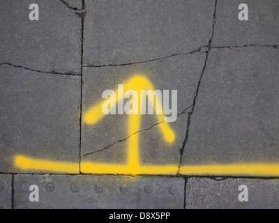 gelb lackierte Pfeil auf grauen Asphalt Stockfoto
