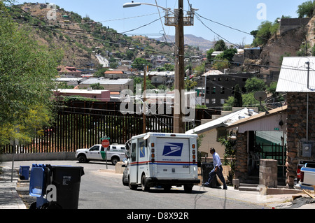Ein US-Postbeamter liefert Post zu einer Residenz in der Nähe der Grenzmauer in Nogales, Arizona, USA, gegenüber von Sonora, Mexiko. Stockfoto