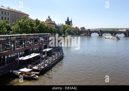 Ein Restaurant neben dem Fluss Vltava mit der Karlsbrücke im Hintergrund, Prag, Tschechische Republik, Europa. Stockfoto