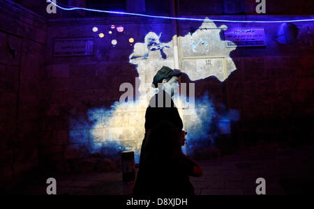 Ein Fußgänger Pass projiziert eine Licht-Show über das griechisch-orthodoxe Patriarchat Gebäude in Christian Quarter in Jerusalem Festival of Lights am 5. Juni 2013. Das Festival findet jährlich rund um die Altstadt Jerusalems mit Spezialeffekten beleuchten historische Stätten. Stockfoto