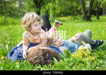 Frau liegt mit ihren beiden Töchtern auf einer Wiese im Frühling Stockfoto