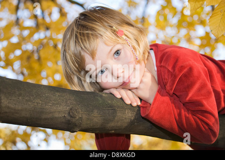 Fünf Jahre altes Mädchen liegen auf dem Bauch auf einem Ast an einem Baum Stockfoto