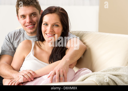 Unbeschwertes junges Paar umarmen einander auf couch Stockfoto