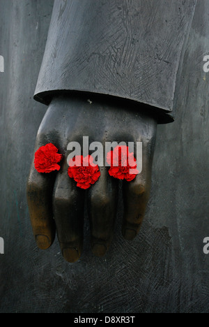 Berlin. Deutschland. Rote Nelken Links zwischen die Finger der Statue Friedrich Engels an Marx-Engels-Forum. Stockfoto