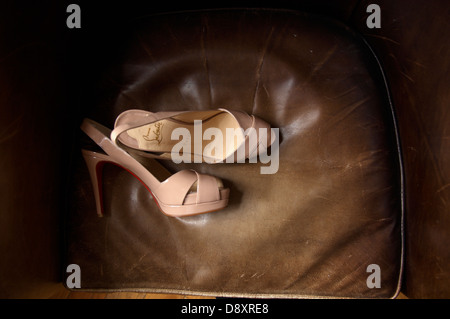 Ein paar rosa hochhackige Schuhe auf einem distressed Lederstuhl gelegt. Stockfoto