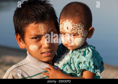 Ein junges Mädchen und Jungen mit aufwendigen Thanaka Gesicht Dekoration U Bein Brücke Teakholz Myanmars 3 Stockfoto