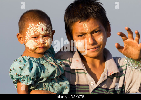 Ein junges Mädchen und Jungen mit aufwendigen Thanaka Gesicht Dekoration U Bein Brücke Teakholz Myanmars 2 Stockfoto