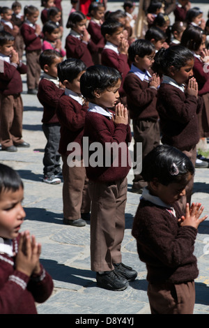 Ein primäres Schulkind betet während Schulversammlung in der Himalaya-Stadt Bharmour, Himachal Pradesh, Indien Stockfoto