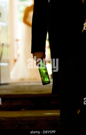 Ein Bräutigam tragen eine leere Bierflasche im Licht. Stockfoto