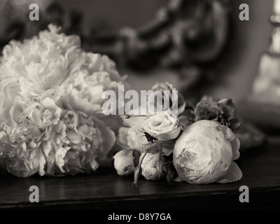 Ein Brautstrauß, mit Pfingstrosen und Rosen, platziert auf einem Holztisch. Stockfoto