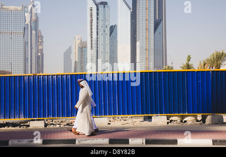 Vereinigte Arabische Emirate, Dubai, arabische Männer gekleidet in traditionellen Dishdasha Baustelle mit Sheikh Zayed Road hinter Vorbeigehen Stockfoto