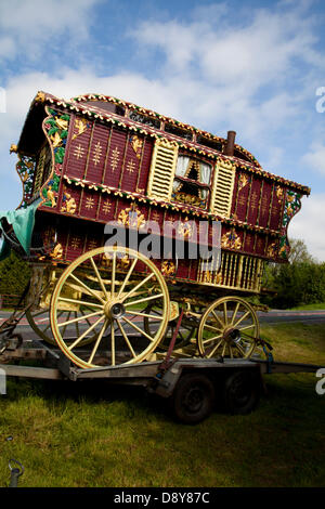 Roma-Reisende Zigeunerwagen, roter vanner-Wagen, vardo, Wohnwagen mit Bugspitze, traditioneller Pferdewagen, Planwagen mit kunstvoll verzierten Karren und Wohnwagen, Travellers Cart in Appleby, Cumbria, Großbritannien. Juni 2013. Fein dekoriertes Vardo oder Bow Top Wagon, ländliches Wohnwagen-Haus, auf dem Weg zur Appleby Horse Fair in Cumbria. Die Messe ist ein jährliches Treffen von Zigeunern und Reisenden, das in der ersten Juniwoche stattfindet und seit der Regierungszeit von James II. Stattfindet, der 1685 eine königliche Charta für eine Pferdemesse in der Nähe des Flusses Eden erteilte. Stockfoto