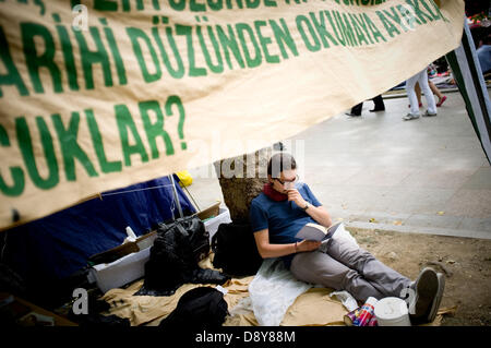 Istanbul, Türkei. 6. Juni 2013. Eine Jugend liest ein unter einem Banner. Nach einigen Tagen des Konflikts war die Taksim-Platz in Istanbul ruhig am 6. Juni mit Menschen kampieren und skandierten Parolen gegen die Regierung. Bildnachweis: Jordi Boixareu/Alamy Live-Nachrichten Stockfoto