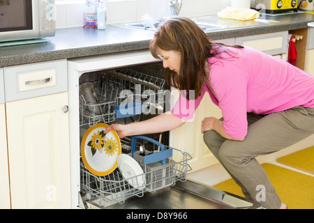 Frau beim Laden der Spülmaschine Stockfoto