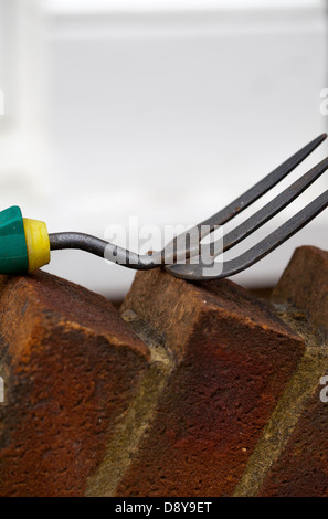 Gartenarbeit-Gabel auf Ziegelmauer Stockfoto
