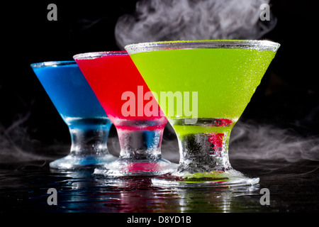 hellen Mini Martinis serviert auf einem nassen dunklen bar oben mit Nebel für einen dramatischen Effekt Stockfoto