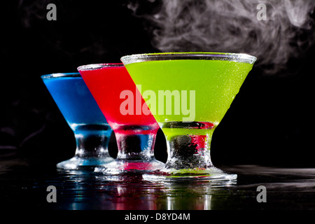 hellen Mini Martinis serviert auf einem nassen dunklen bar oben mit Nebel für einen dramatischen Effekt Stockfoto