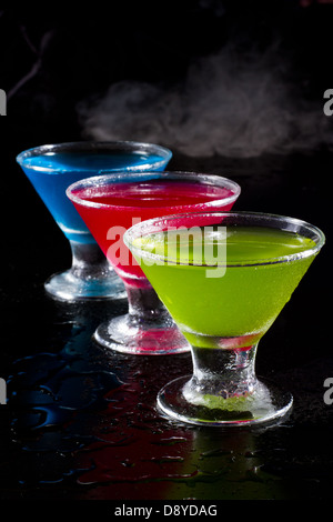 hellen Mini Martinis serviert auf einem nassen dunklen bar oben mit Nebel für einen dramatischen Effekt Stockfoto