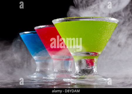 hellen Mini Martinis serviert auf einem nassen dunklen bar oben mit Nebel für einen dramatischen Effekt Stockfoto