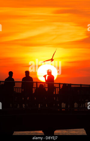 Aberystwyth, Wales, UK. 6. Juni 2013.   Am Ende eines anderen Tages warme Sonnentage mit Temperaturen in den niedrigen 20er Jahren Grad Celsius, eine Gruppe von Menschen sind bei Sonnenuntergang am Ende der viktorianischen Seestadt Pier in Aberystwyth Wales UK Foto von Keith Morris/Alamy trinken Live-Nachrichten Stockfoto