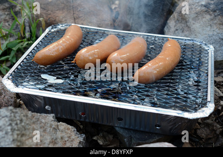 Würste Kochen auf einem Einweg-Grill im freien Stockfoto