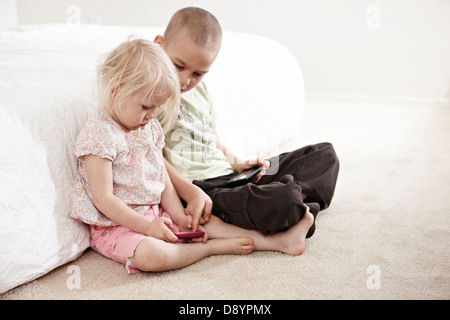 Jungen und Mädchen spielen auf MP3-player Stockfoto