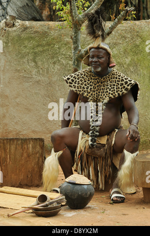 Menschen, älterer Erwachsener, Zulu-Chef, Festkleid, Sitzen, Topf mit traditionellem afrikanischem Bier, ethnisch, Shakaland, KwaZulu-Natal, Südafrika Stockfoto