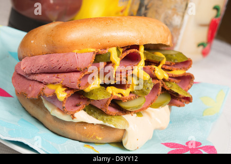 Ein schlichter Bagel gefüllt mit Pastrami, in Scheiben geschnittenen Gurken, Senf und Chili-Mayonnaise. Stockfoto