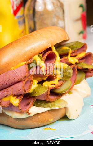 Ein schlichter Bagel gefüllt mit Pastrami, in Scheiben geschnittenen Gurken, Senf und Chili-Mayonnaise. Stockfoto