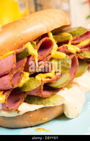 Ein schlichter Bagel gefüllt mit Pastrami, in Scheiben geschnittenen Gurken, Senf und Chili-Mayonnaise. Stockfoto