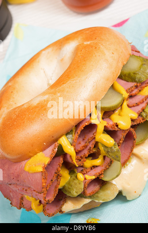 Ein schlichter Bagel gefüllt mit Pastrami, in Scheiben geschnittenen Gurken, Senf und Chili-Mayonnaise. Stockfoto